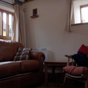A comfortable lounge area featuring a plush brown leather sofa beside a wooden rocking chair.