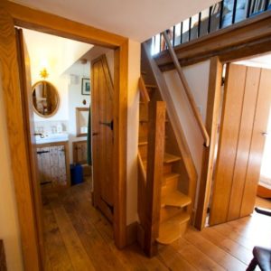 A wooden staircase leading to a bright landing area showcasing solid oak floorboards and traditionally crafted paneled wooden doors.